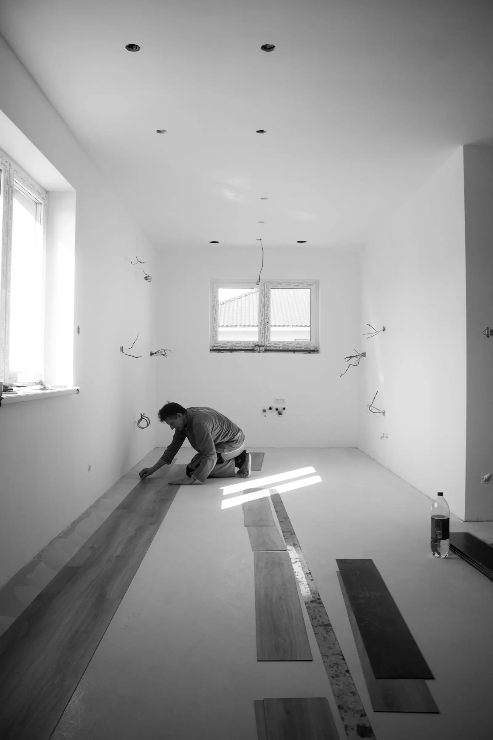 Illustrative photo of an installer laying engineered hardwood planks in an empty room