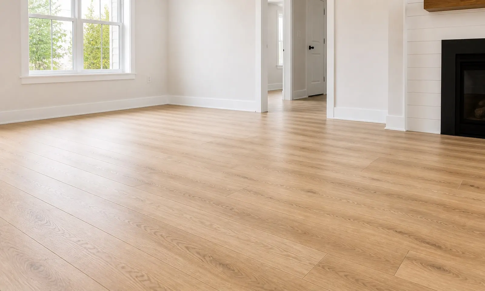 Light wood-look laminate floor installed through an open room with white trim